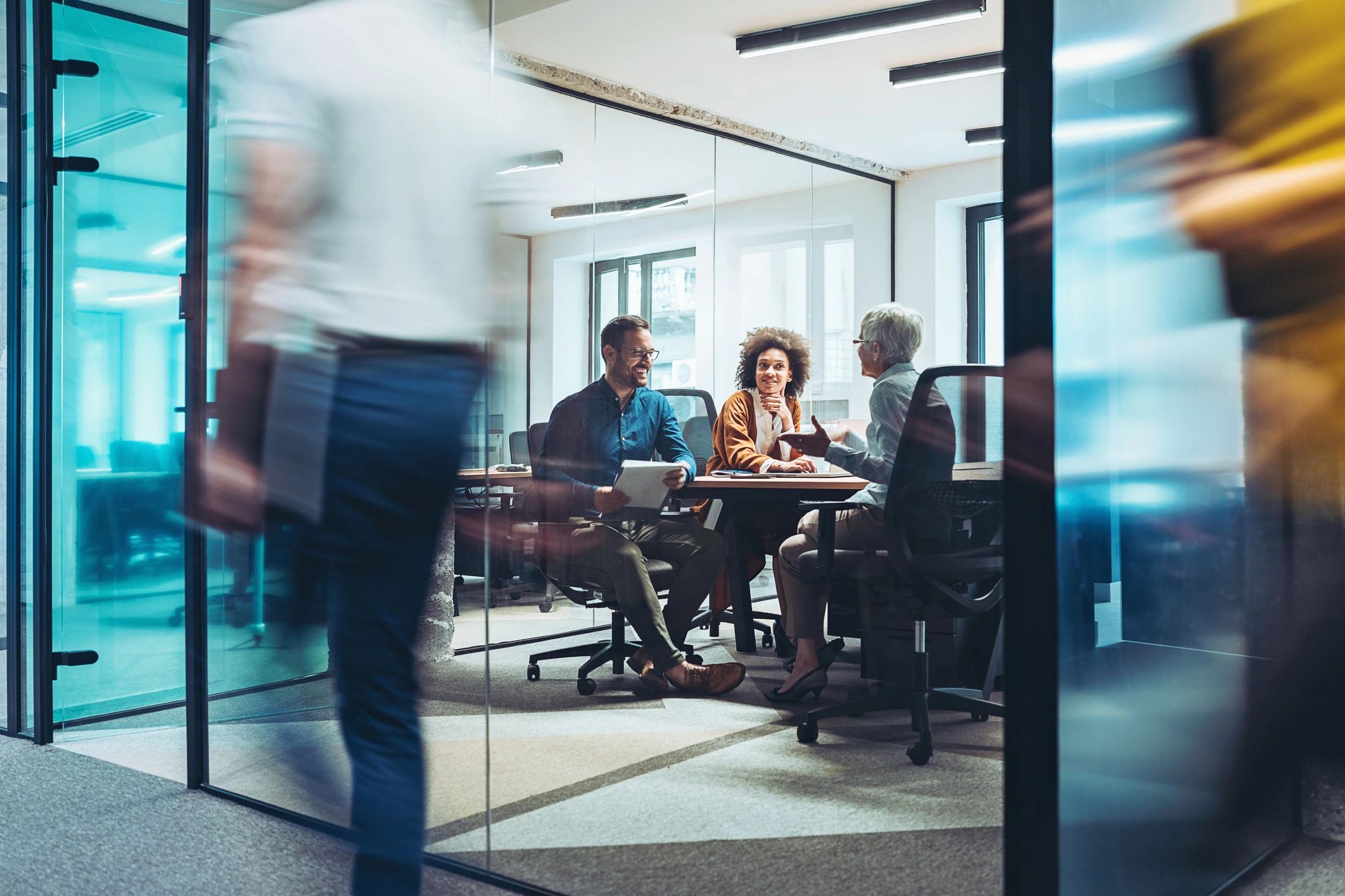 Three colleagues having a meeting in a modern glass office.