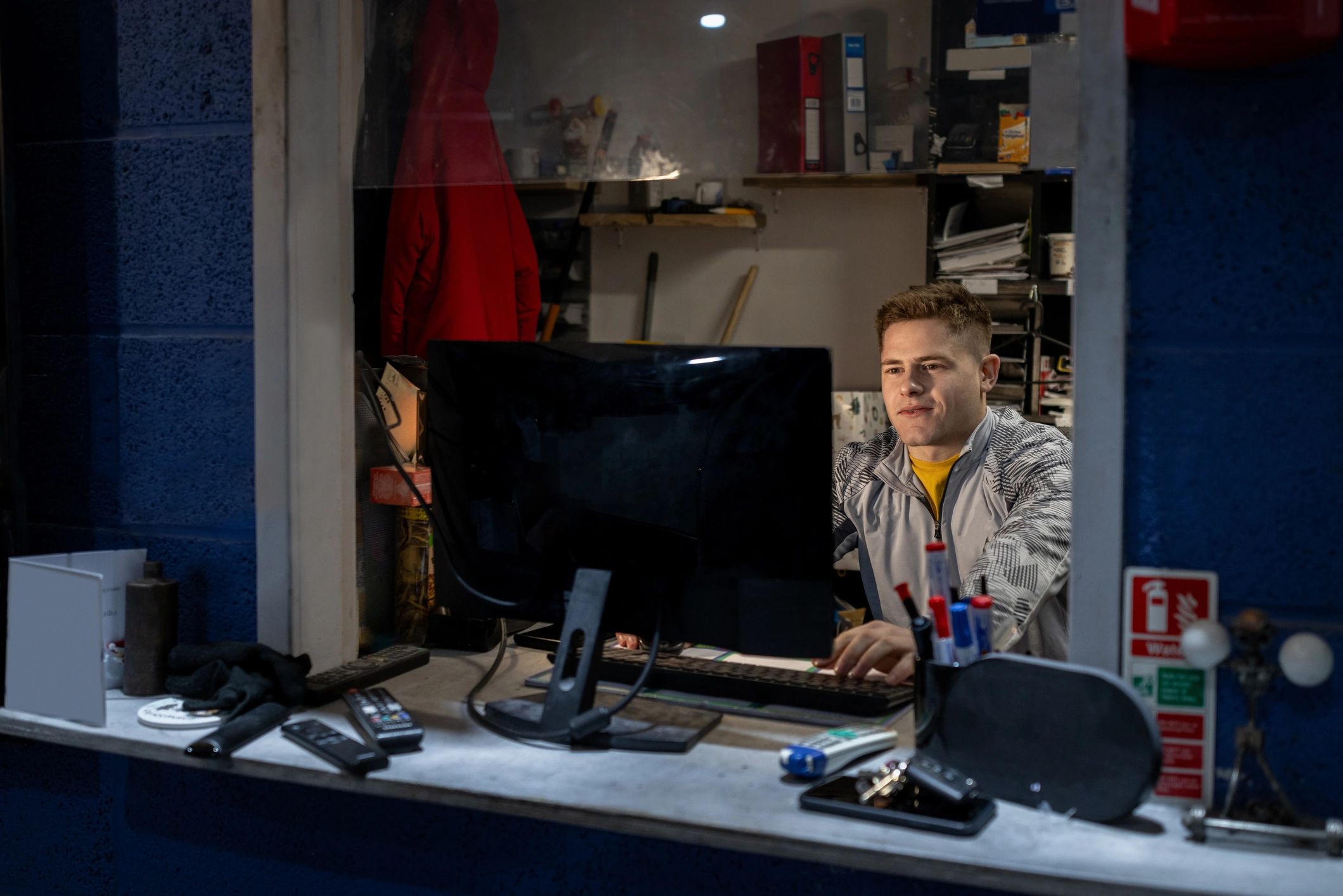 Man working on a computer in a small office with blue walls.